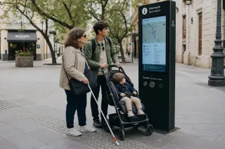 A woman with a white cane and a man with a stroller consult an accessible information kiosk in a city square with tactile pavement and soft, natural light.